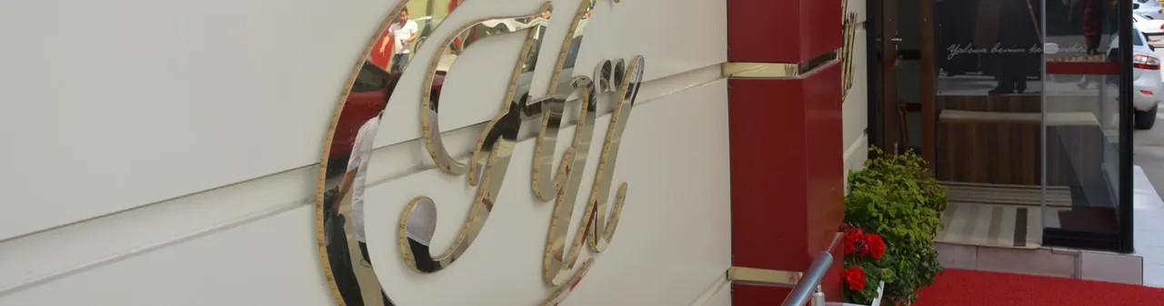 Hotel Ülke girişi: duvarda “HÜ” monogramı, kapı önünde kırmızı halı